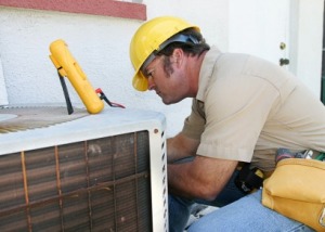 An air conditioning repairman working on a compressor unit.
